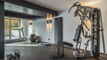Un gimnasio con cinta de correr, pelotas de ejercicio y máquinas de pesas.