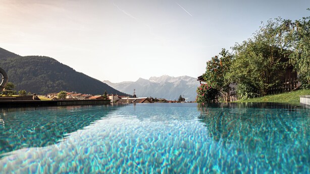 Una piscina cristalina con vistas a las montañas al fondo.