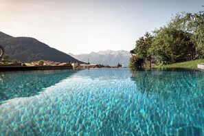 Una piscina cristalina con vistas a las montañas al fondo.