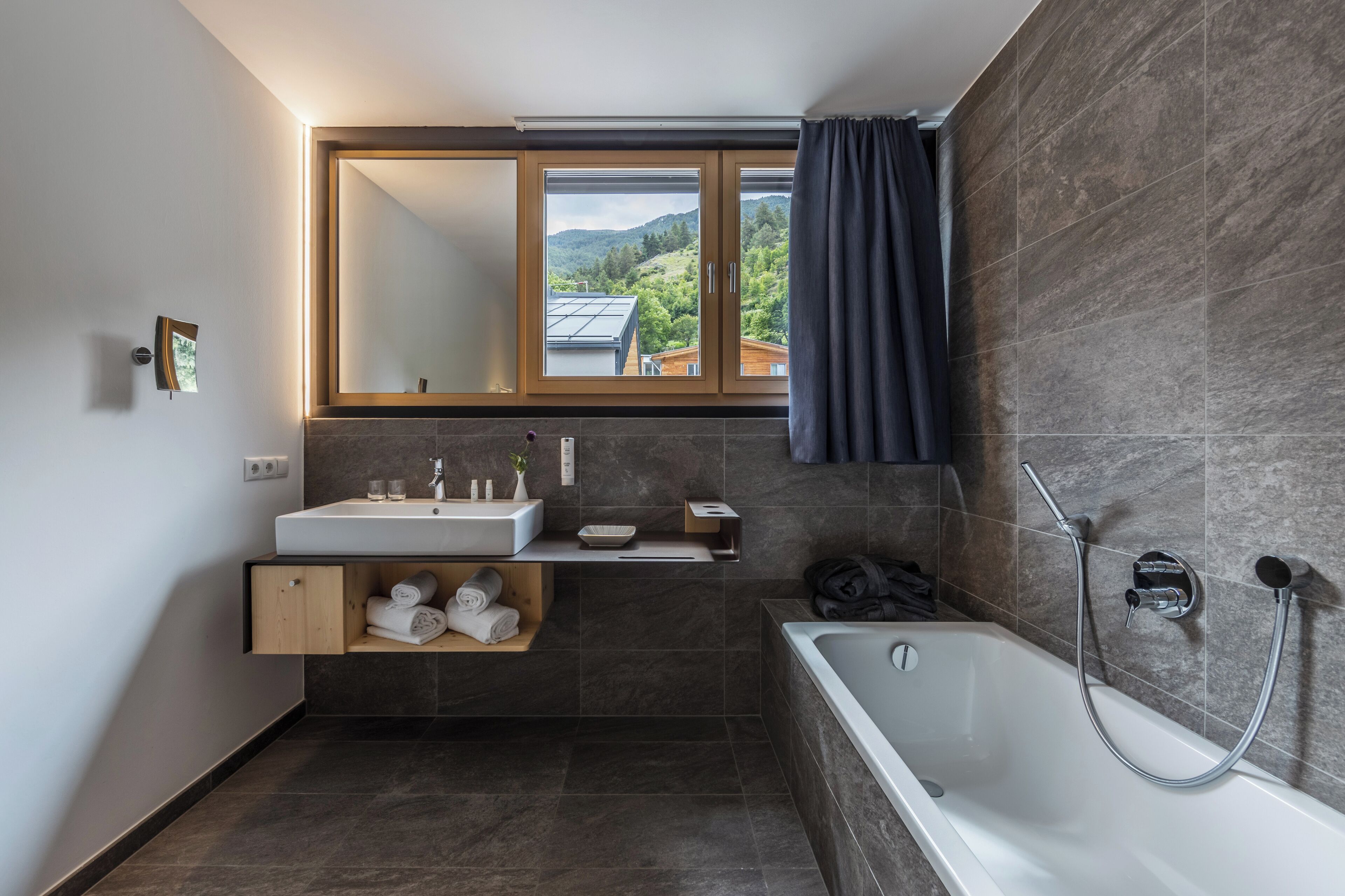 A modern bathroom with a large bathtub, a built-in sink, and a window with a view of the outdoors.