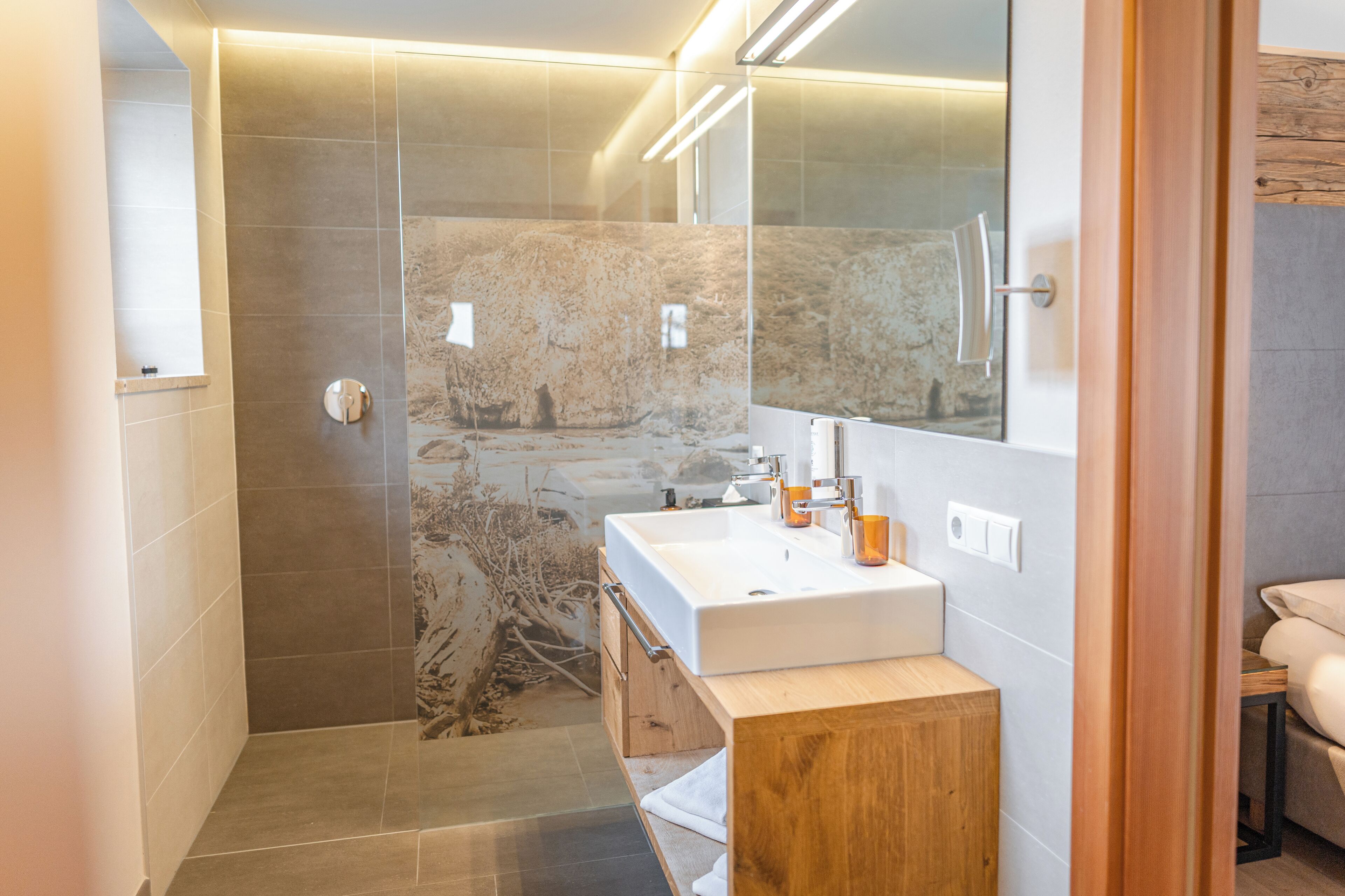 Ein modernes Badezimmer mit Dusche, Waschbecken und Spiegel.
