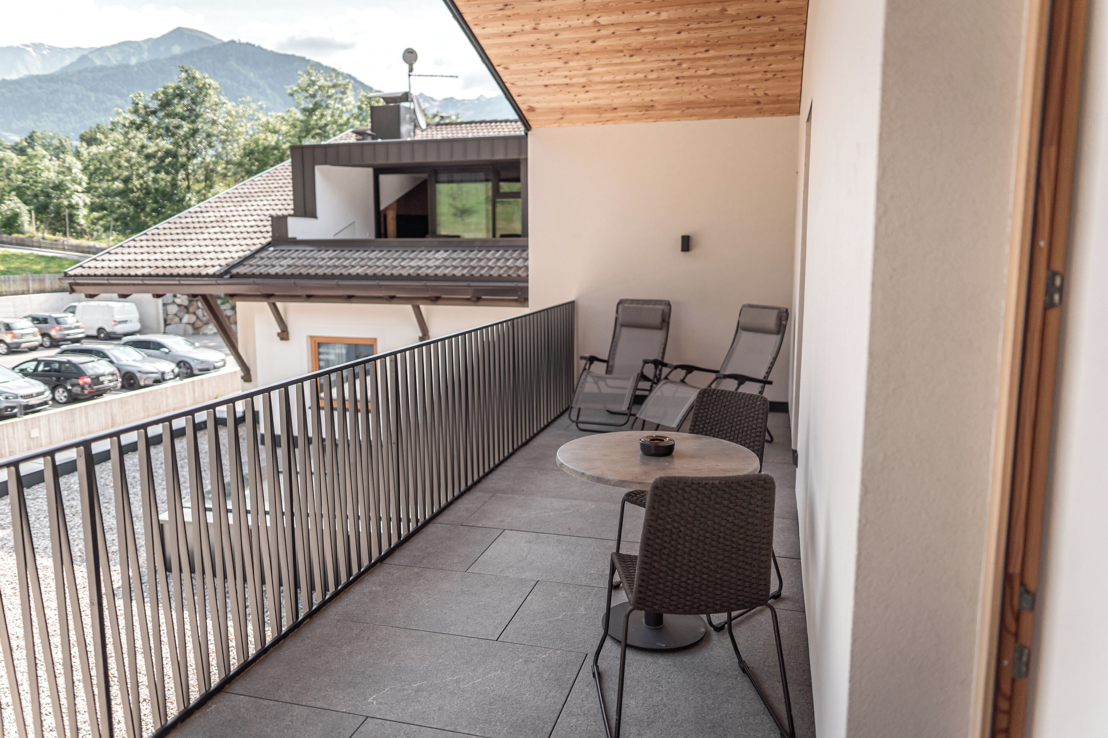 Ein Balkon mit Blick auf geparkte Autos und Berge.
