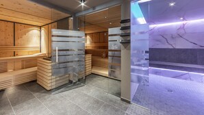 Una sauna moderna con bancos de madera y divisiones de vidrio, suelo de baldosas de mármol e iluminación empotrada.
