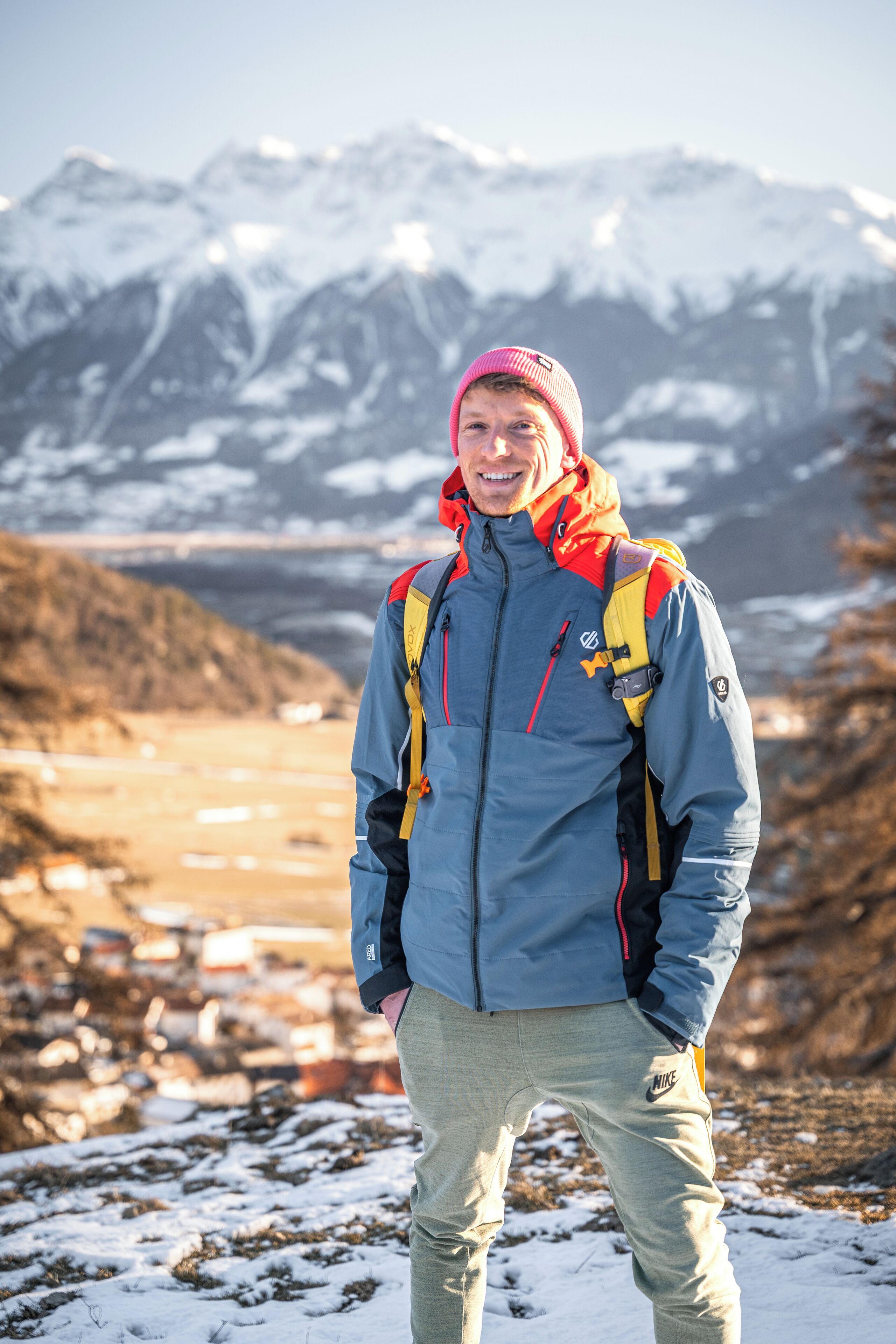 A person standing on a snowy mountain with a backpack, wearing a jacket and pants.