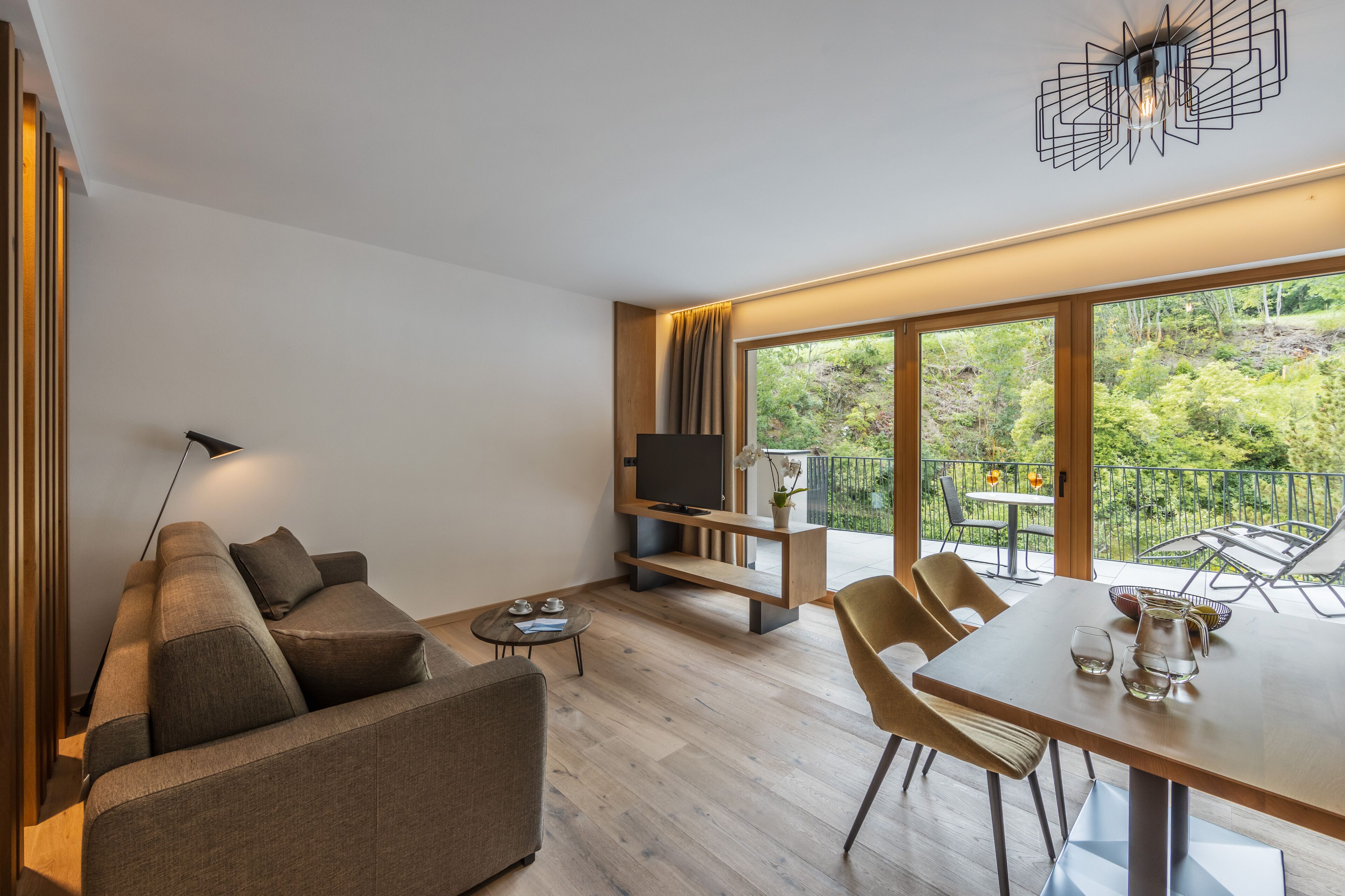Una sala de estar moderna con sofá, televisor, mesa de comedor y sillas.