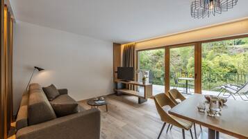 Una sala de estar moderna con sofá, televisor, mesa de comedor y sillas.