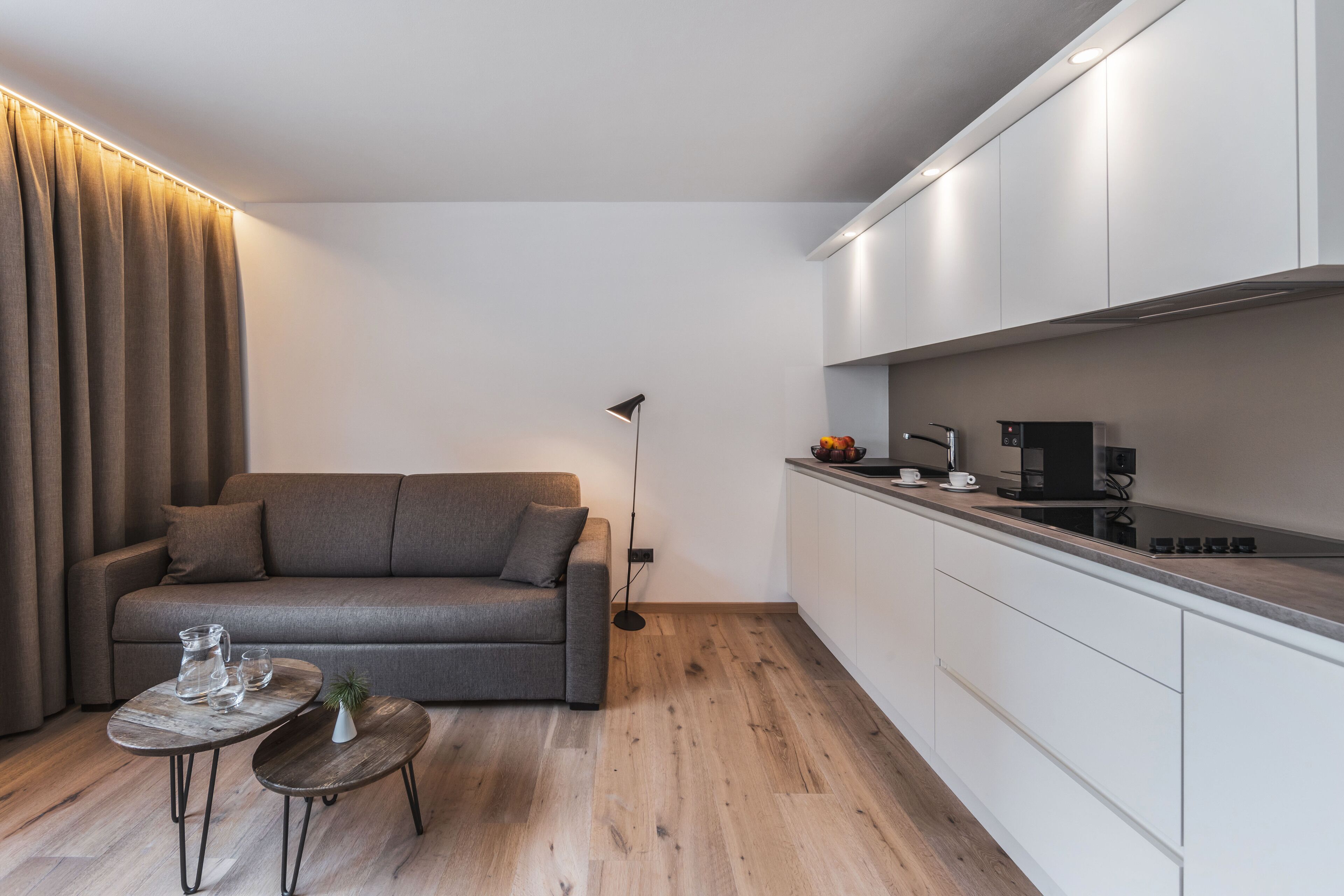 A modern living room with a grey sofa, a small coffee table, and a floor lamp.