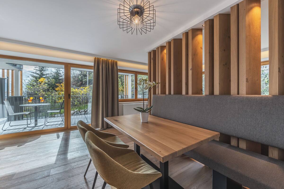 Un espace repas moderne avec une table en bois, un banc rembourré et des chaises en osier.