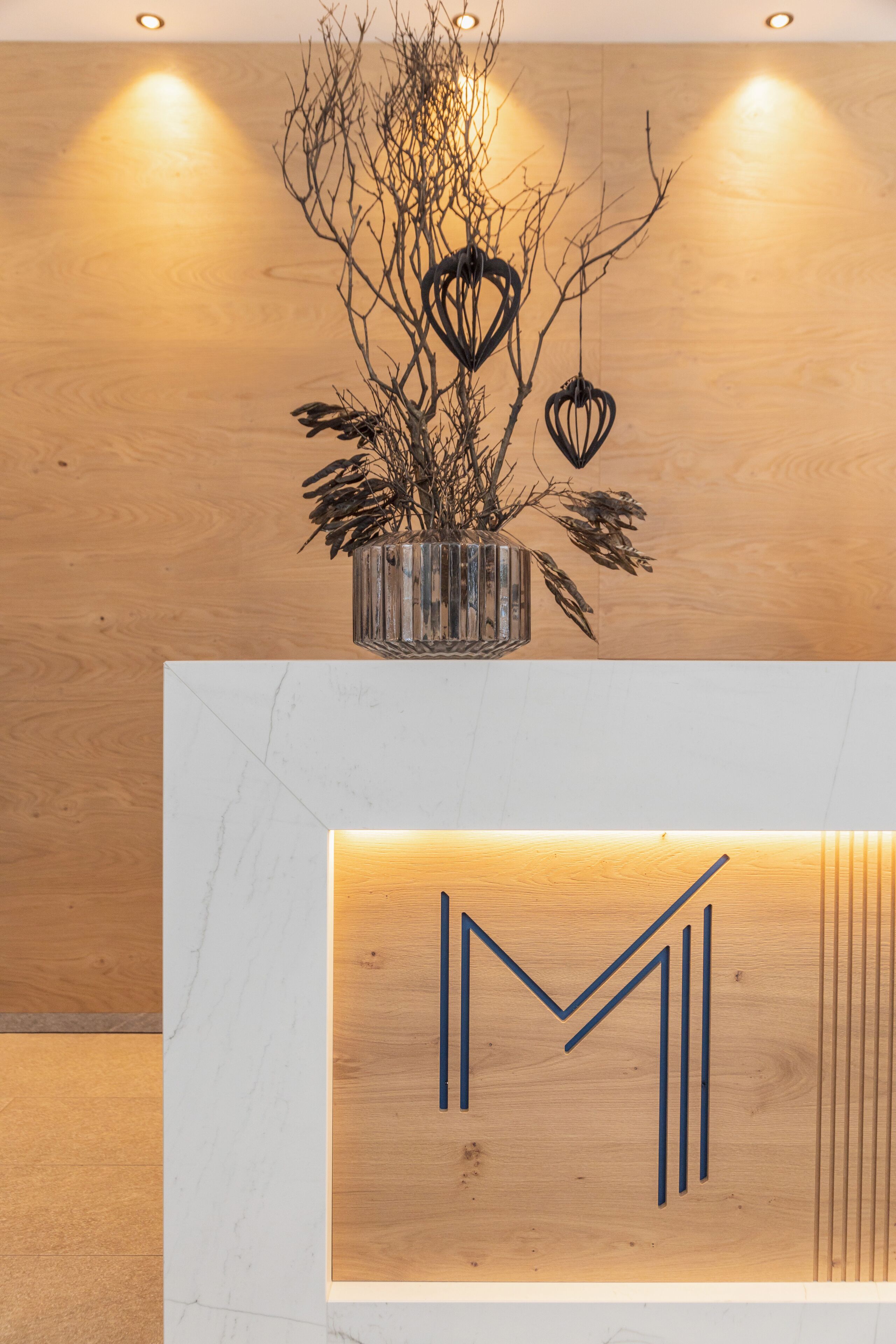 A wooden wall with a hanging light fixture and a framed artwork with a geometric design.