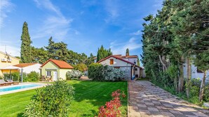 A residential area with a swimming pool, a well-maintained lawn, and a stone pathway. - Luxurious home in Premantura (Premantura)
