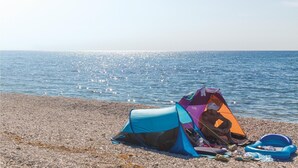 A beach with a tent and a blue inflatable ring. - Luxurious home in Premantura (Premantura)