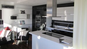 Une cuisine moderne dotée d’un îlot central, d’appareils électroménagers intégrés et d’un coin repas avec un canapé et une table basse.