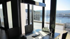 Un espace de restauration moderne comprenant une table, des chaises et une vue sur la ville et l’eau.