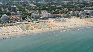 Vista aérea de una ciudad costera con una playa extensa, numerosos edificios y un puerto deportivo.