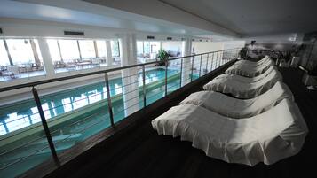 A poolside area with a glass railing, lounge chairs, and a view of the pool.