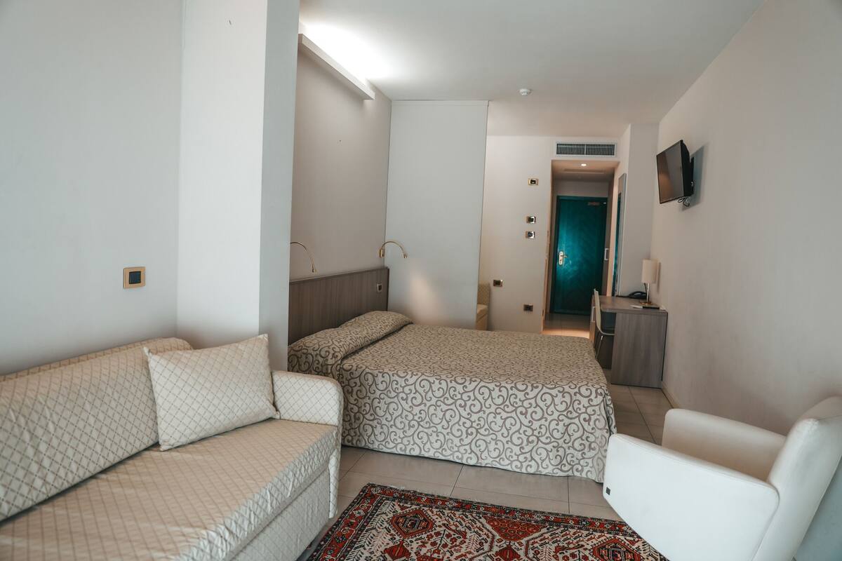 Une chambre d’hôtel comprenant un lit, un canapé, une chaise, un bureau et un téléviseur.