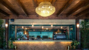Una zona de bar con mostrador de mosaicos, vigas de madera en el techo y lámparas colgantes.
