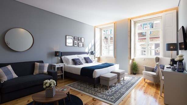 Een moderne slaapkamer met een bed, nachtkastjes, een bank, een bureau en een groot raam.