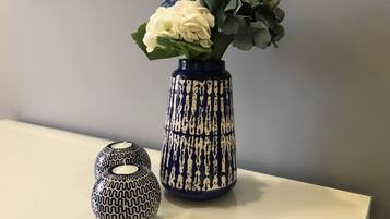 A vase with a blue and white pattern, a white flower, and a decorative object on a table.
