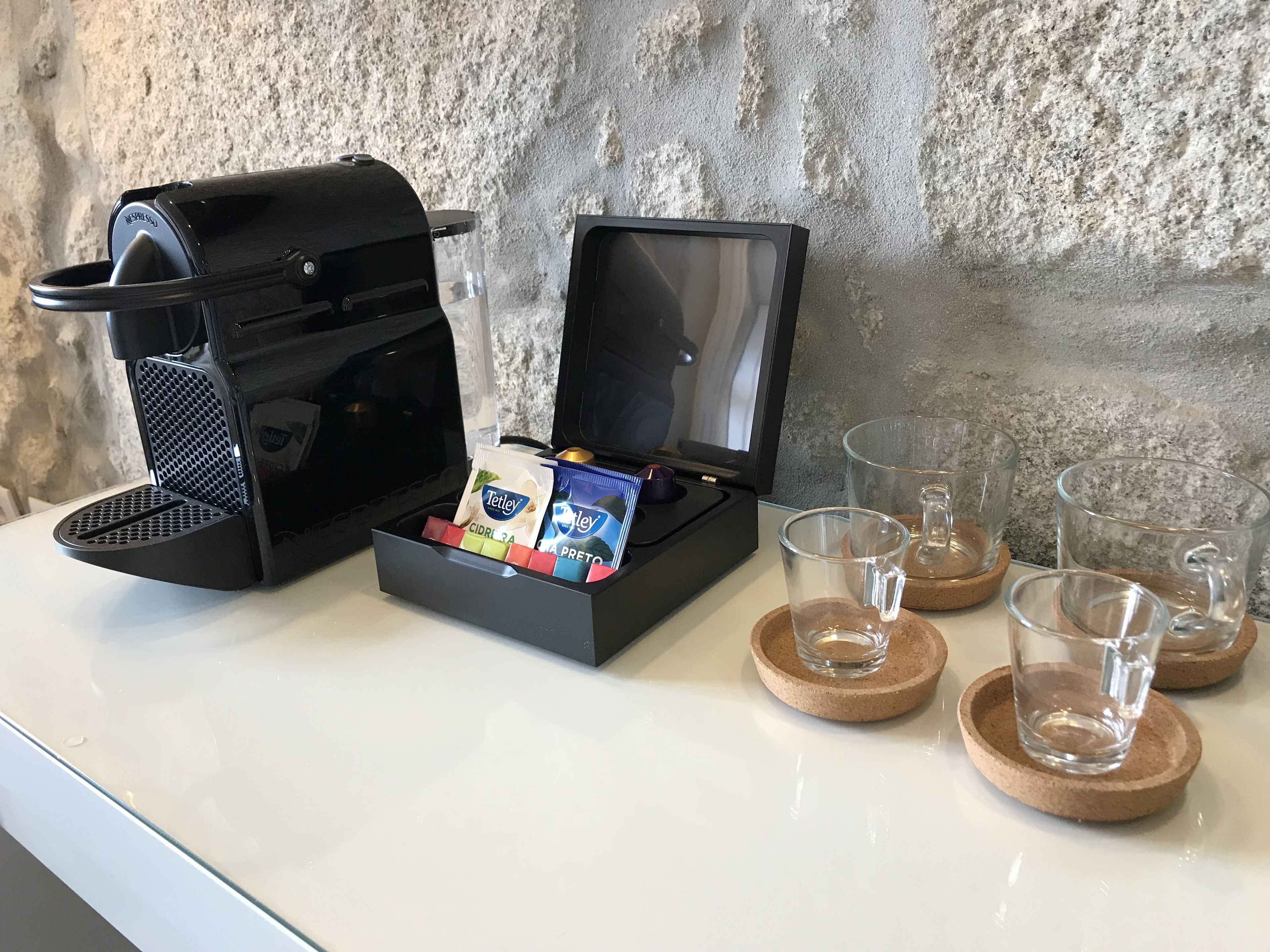 A coffee maker with a coffee pod holder, two glasses, and a water glass on a white countertop.