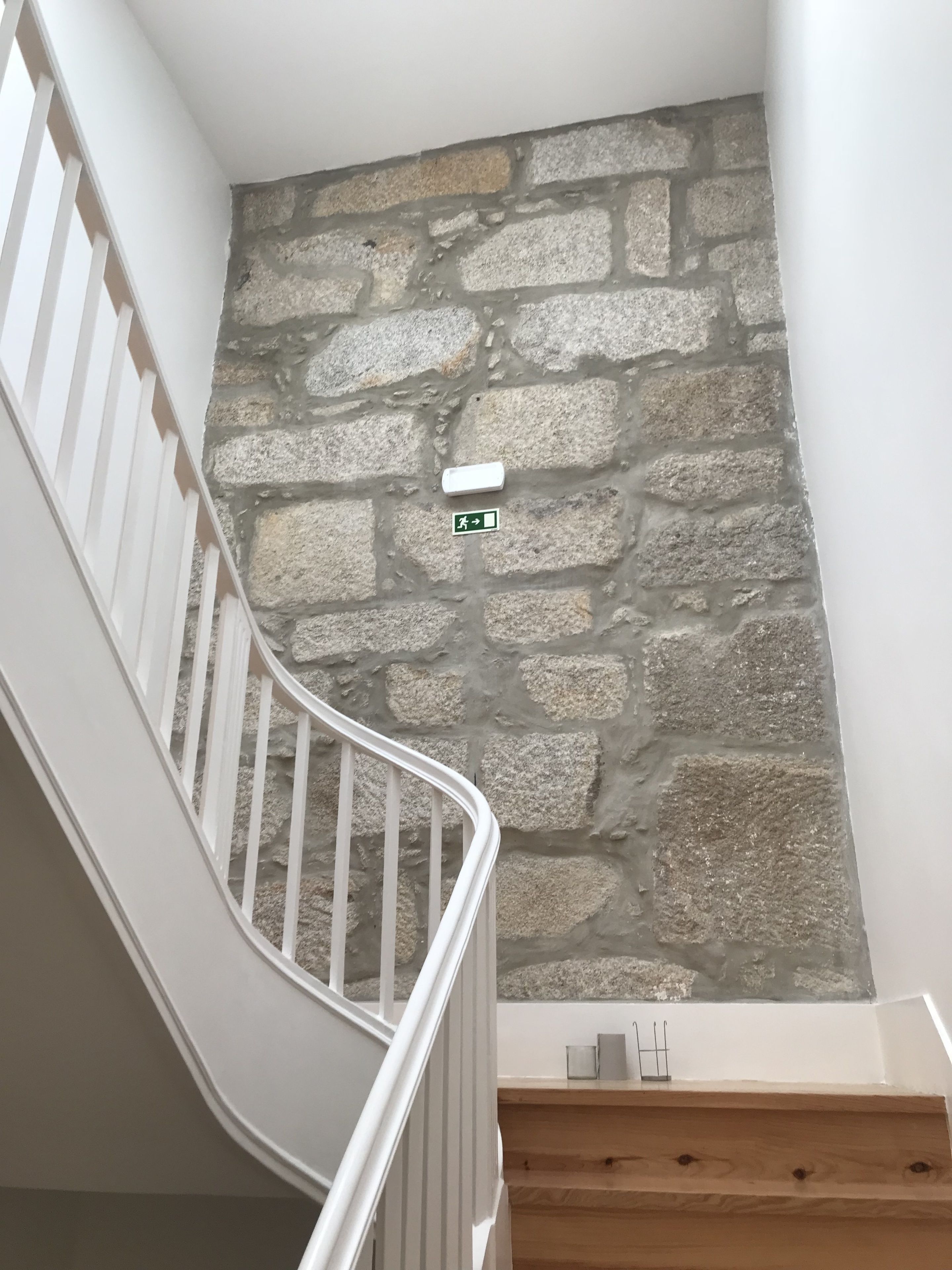 Una escalera con barandillas blancas y un muro de piedra.