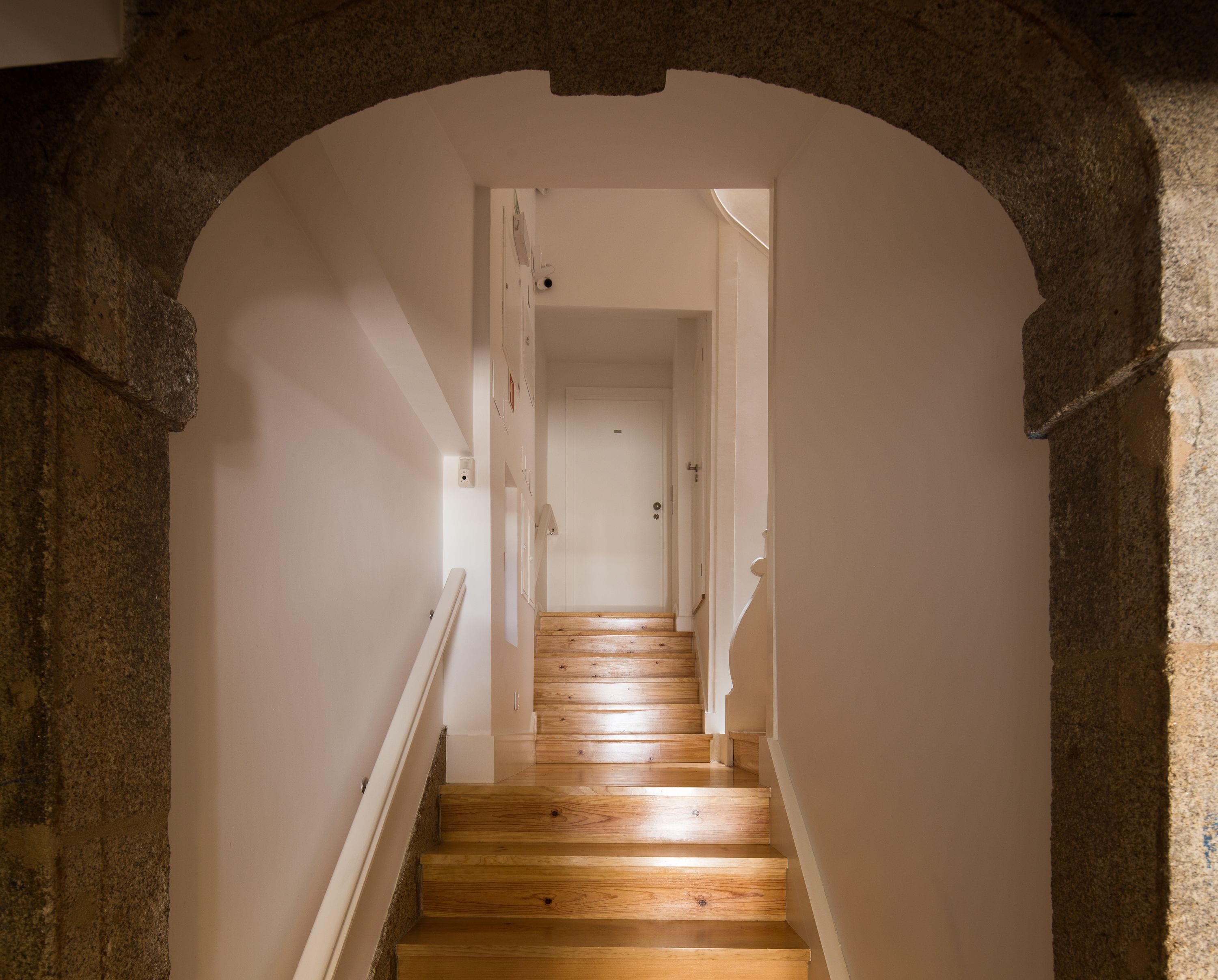 A staircase with wooden steps and white railings, leading to a door at the top.