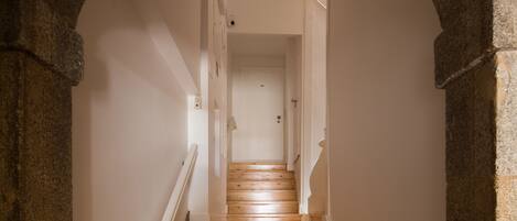 A staircase with wooden steps and white railings, leading to a door at the top.