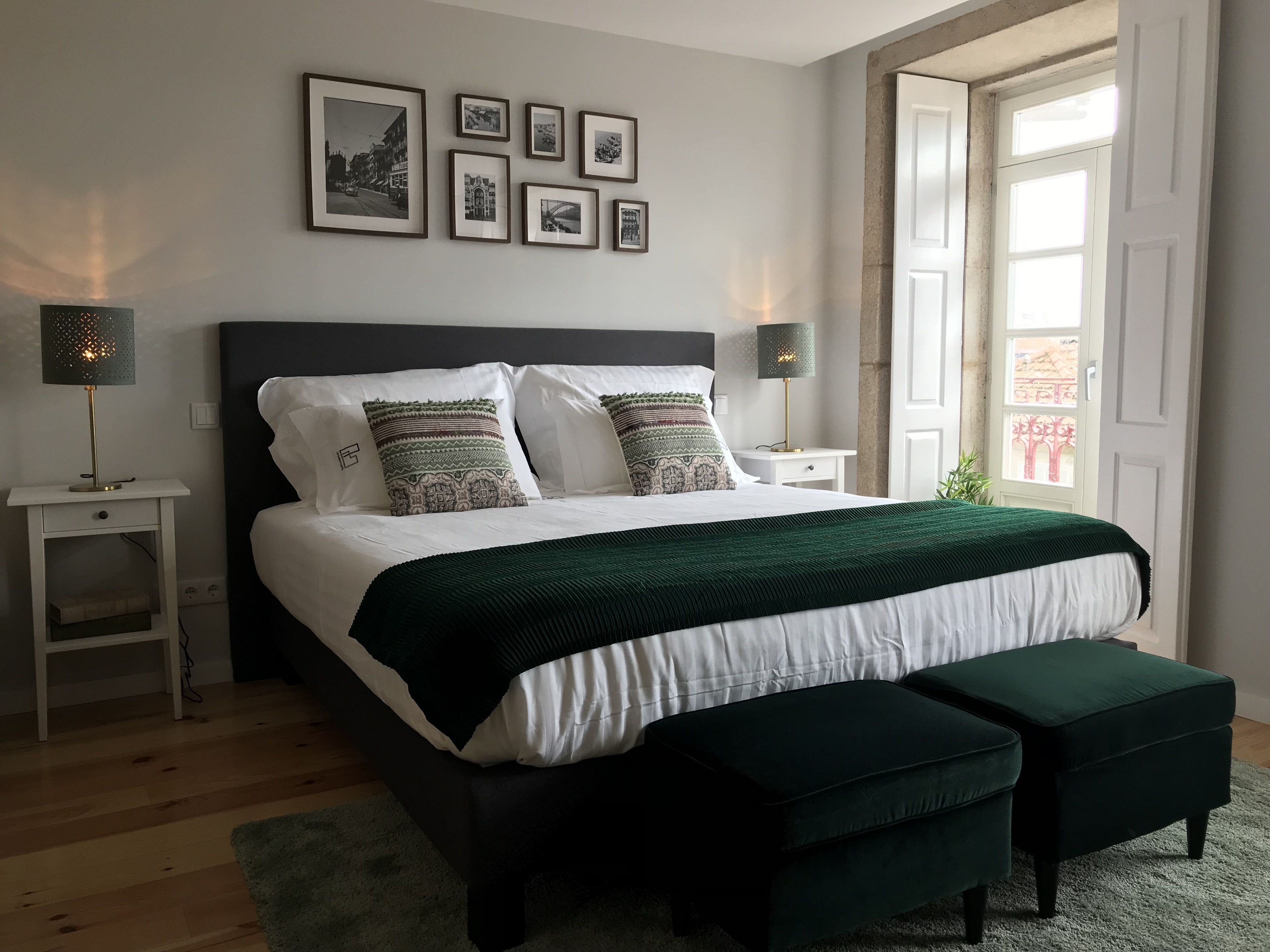 A bedroom with a bed, bedside tables, a bench, and a window.