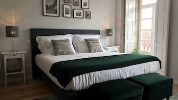 A bedroom with a bed, bedside tables, a bench, and a window.