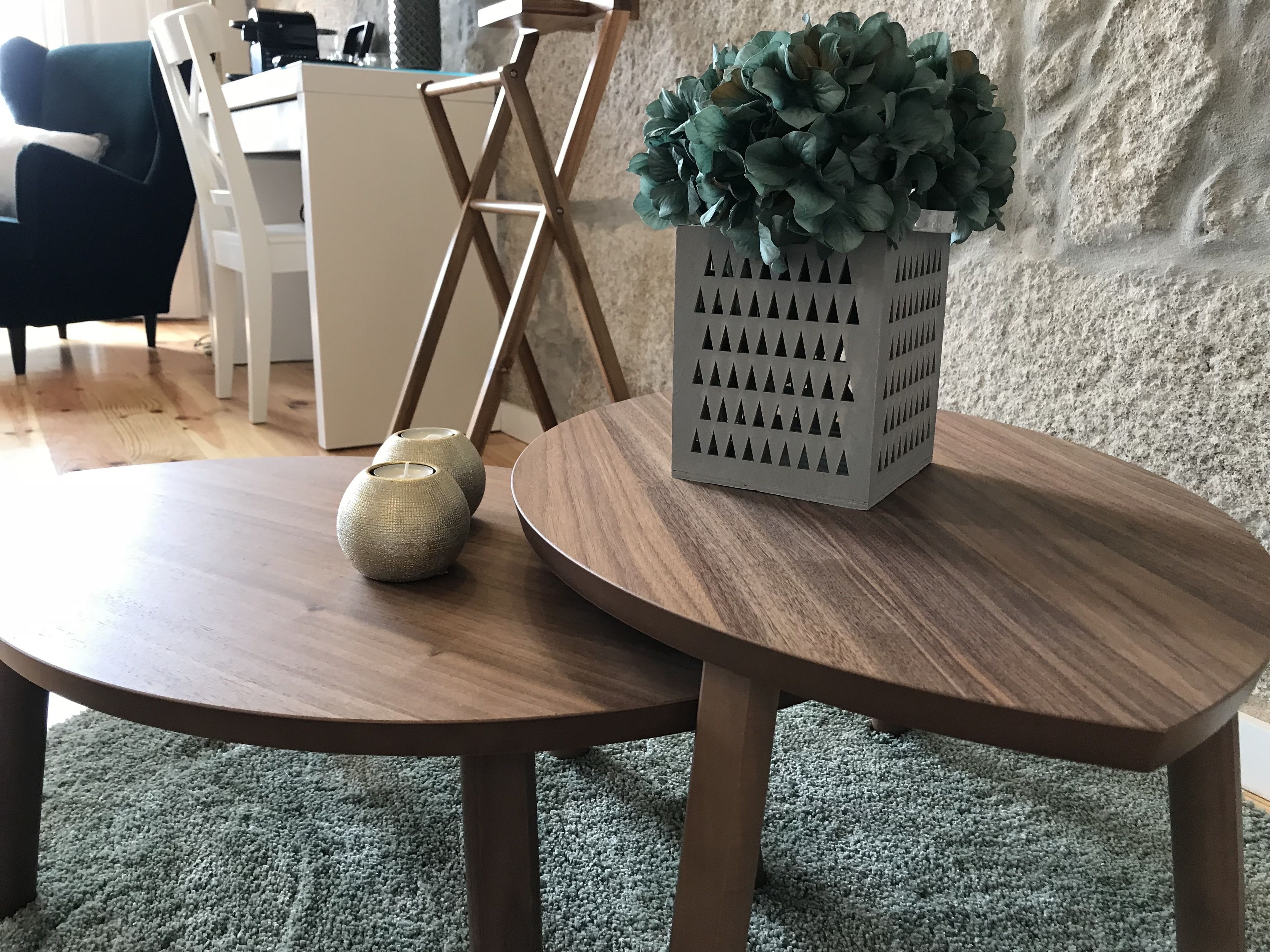 A round wooden table with a white vase and a potted plant.