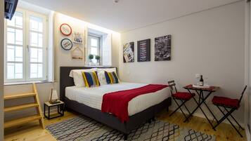 A bedroom with a bed, a window, a desk, and two chairs.