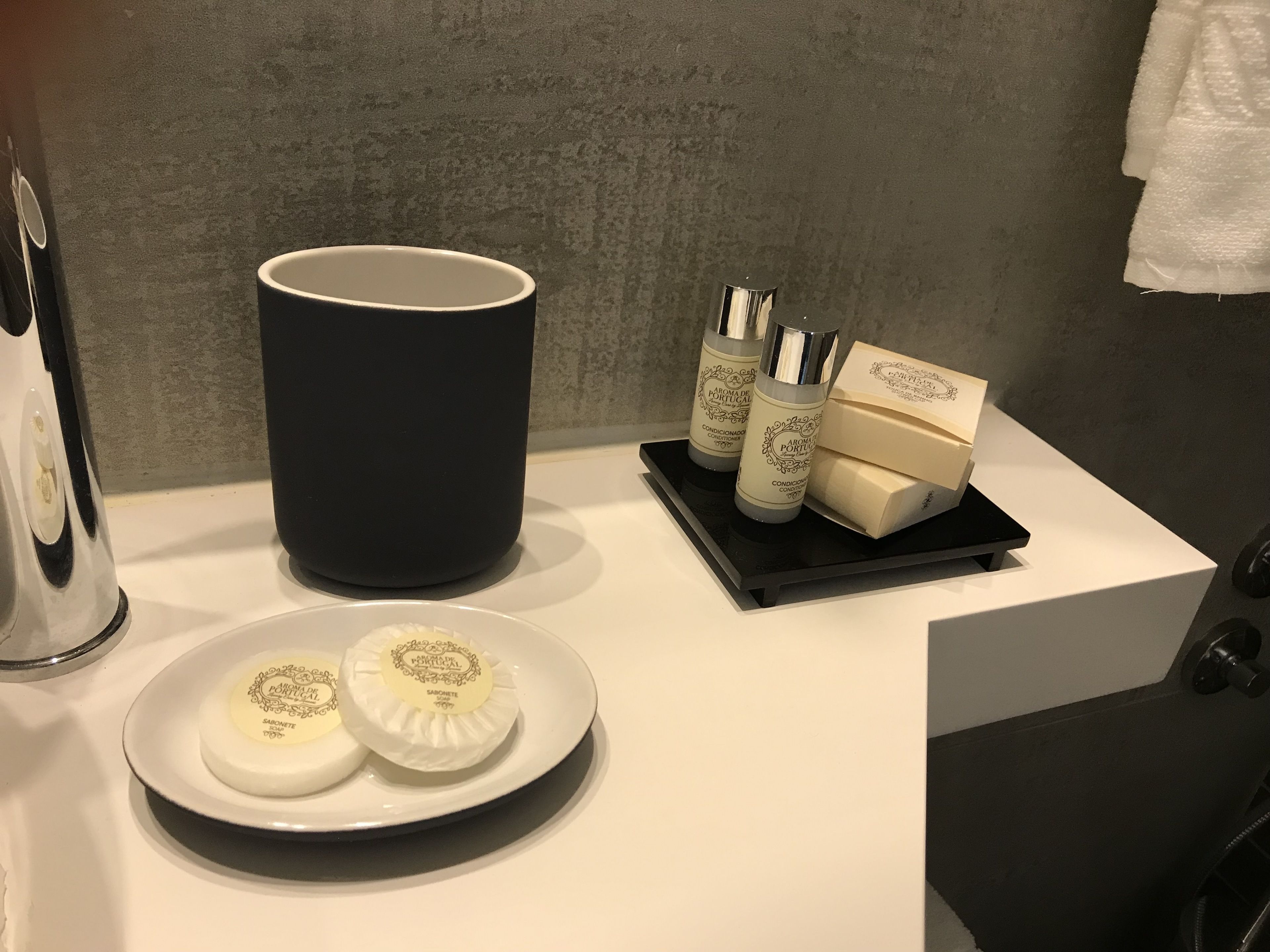 A bathroom counter with a black mug, two soap bars, and two bottles of lotion.