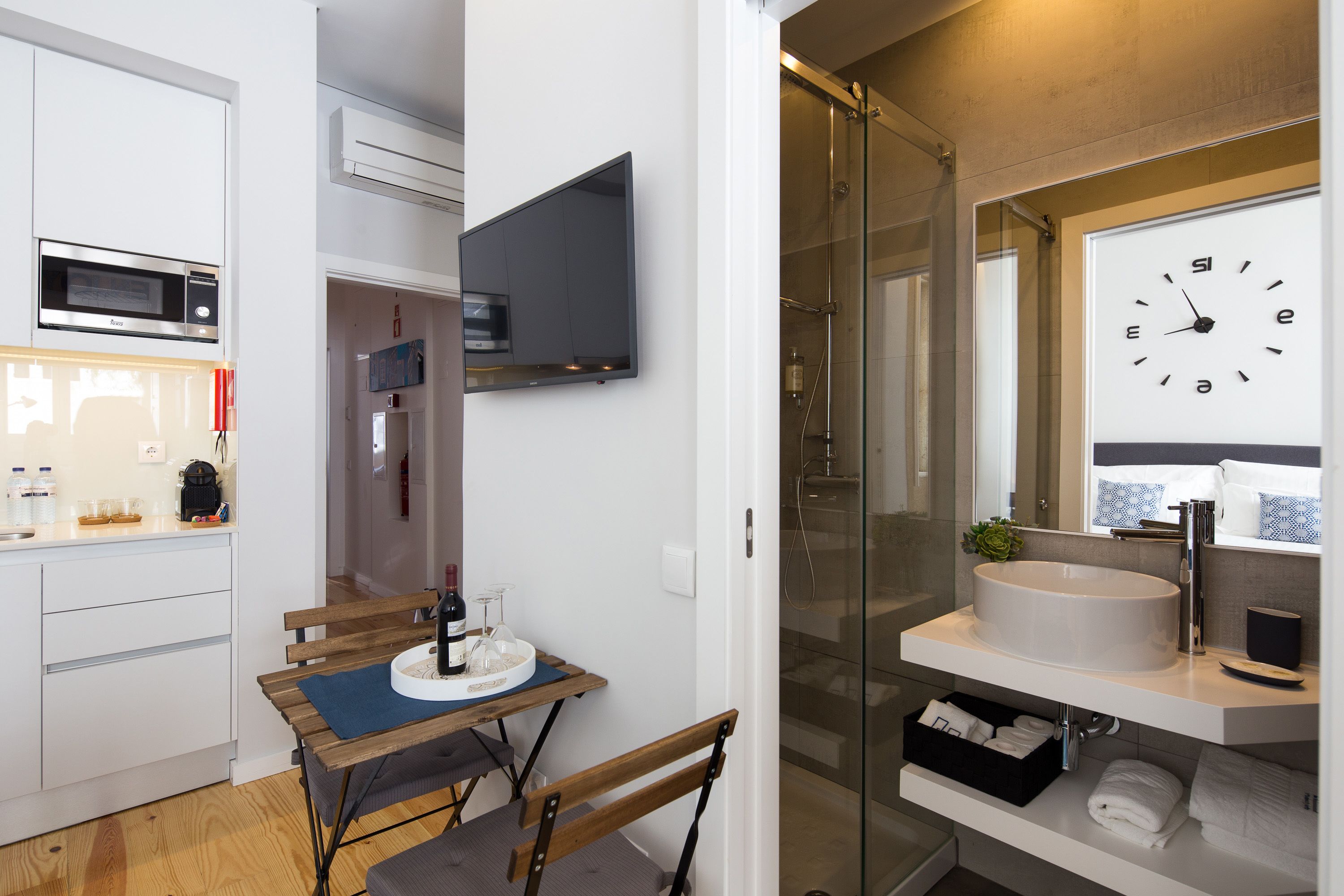 A modern bathroom with a large mirror, a round sink, and a glass-enclosed shower.