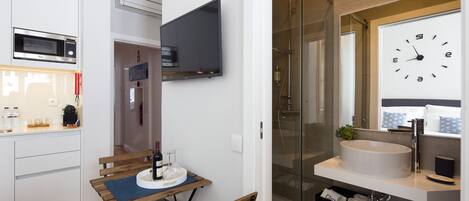 A modern bathroom with a large mirror, a round sink, and a glass-enclosed shower.