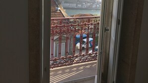 Uitzicht vanaf een balkon met een rode metalen reling, op een waterpartij en een stad met gebouwen en een brug.