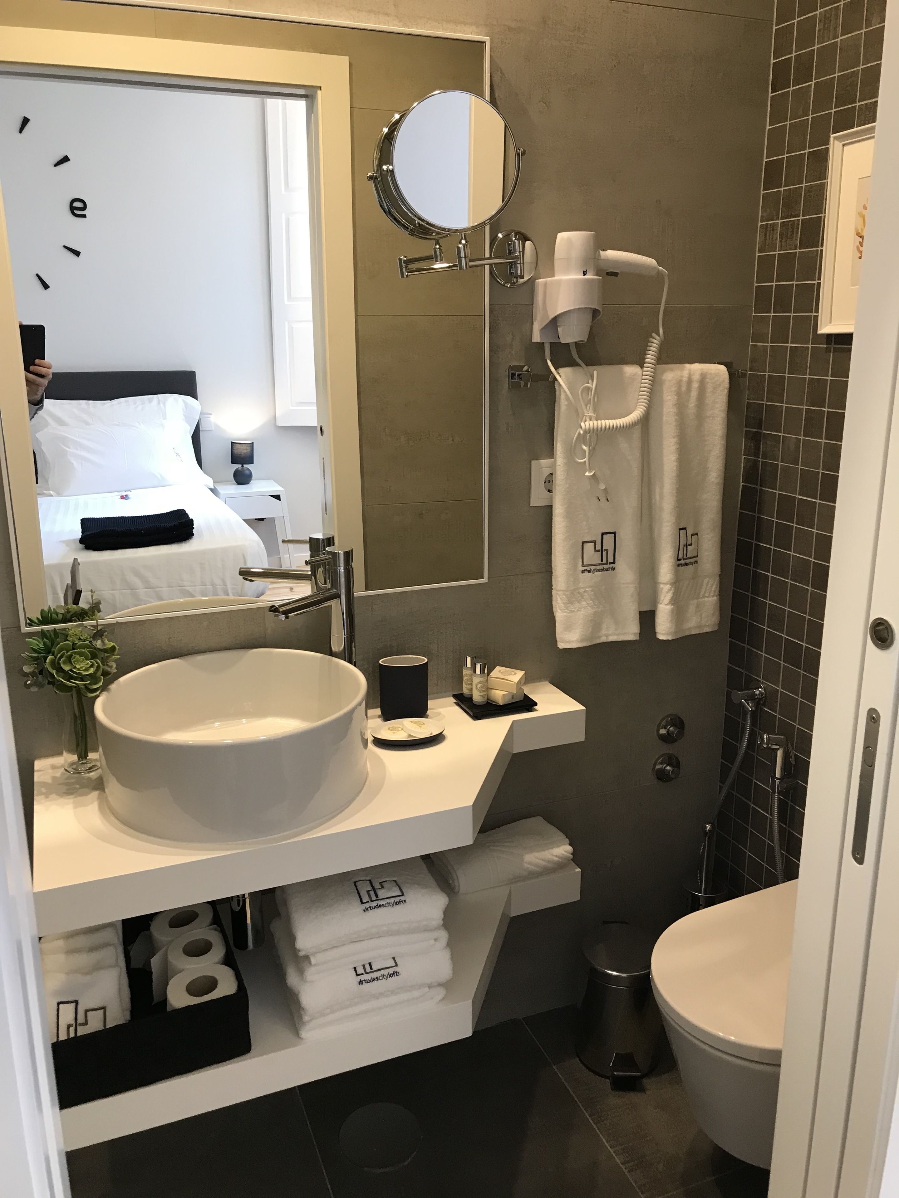 A modern bathroom with a large sink, mirror, towel rack, and a shower area.