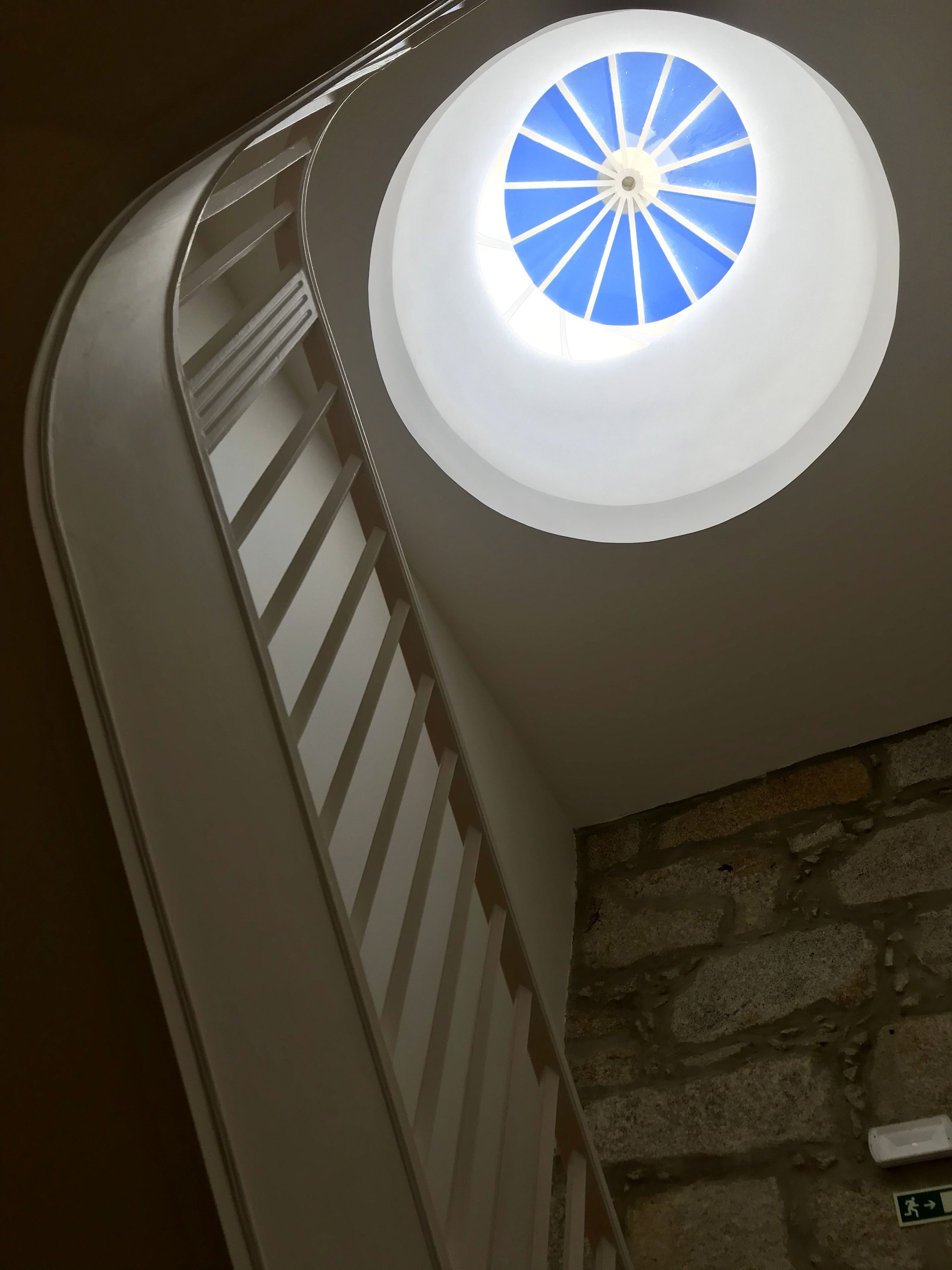 A spiral staircase with a circular skylight.