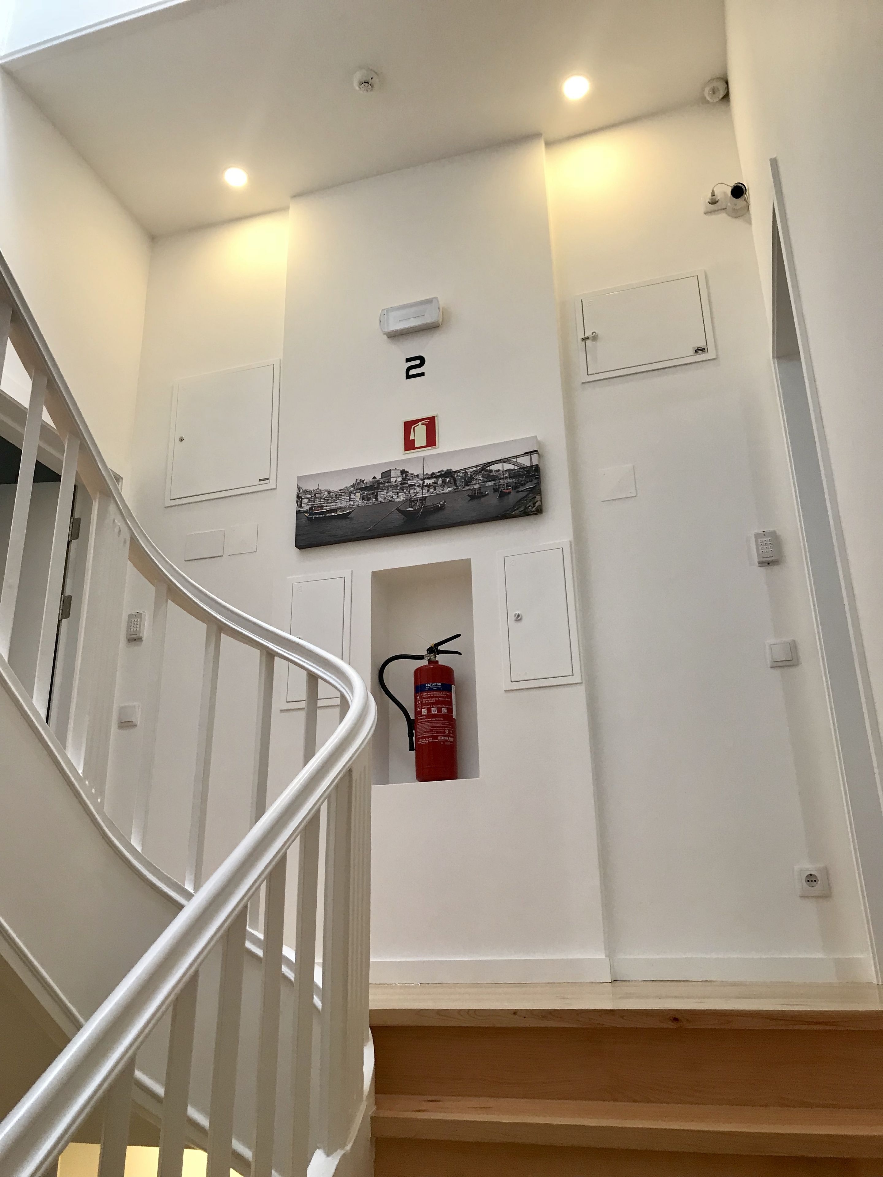 A staircase with a fire extinguisher mounted on the wall, a number 2 sign, and a fire alarm.