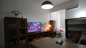 Ein Wohnzimmer mit Fernseher, einem Esstisch und einer Couch.