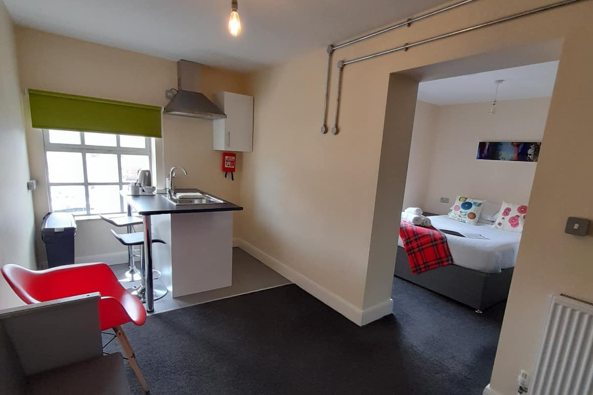 A compact living space with a kitchenette, a dining area, and a bedroom.