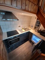 A modern kitchen with a built-in oven, a stainless steel sink, and a wooden ceiling.