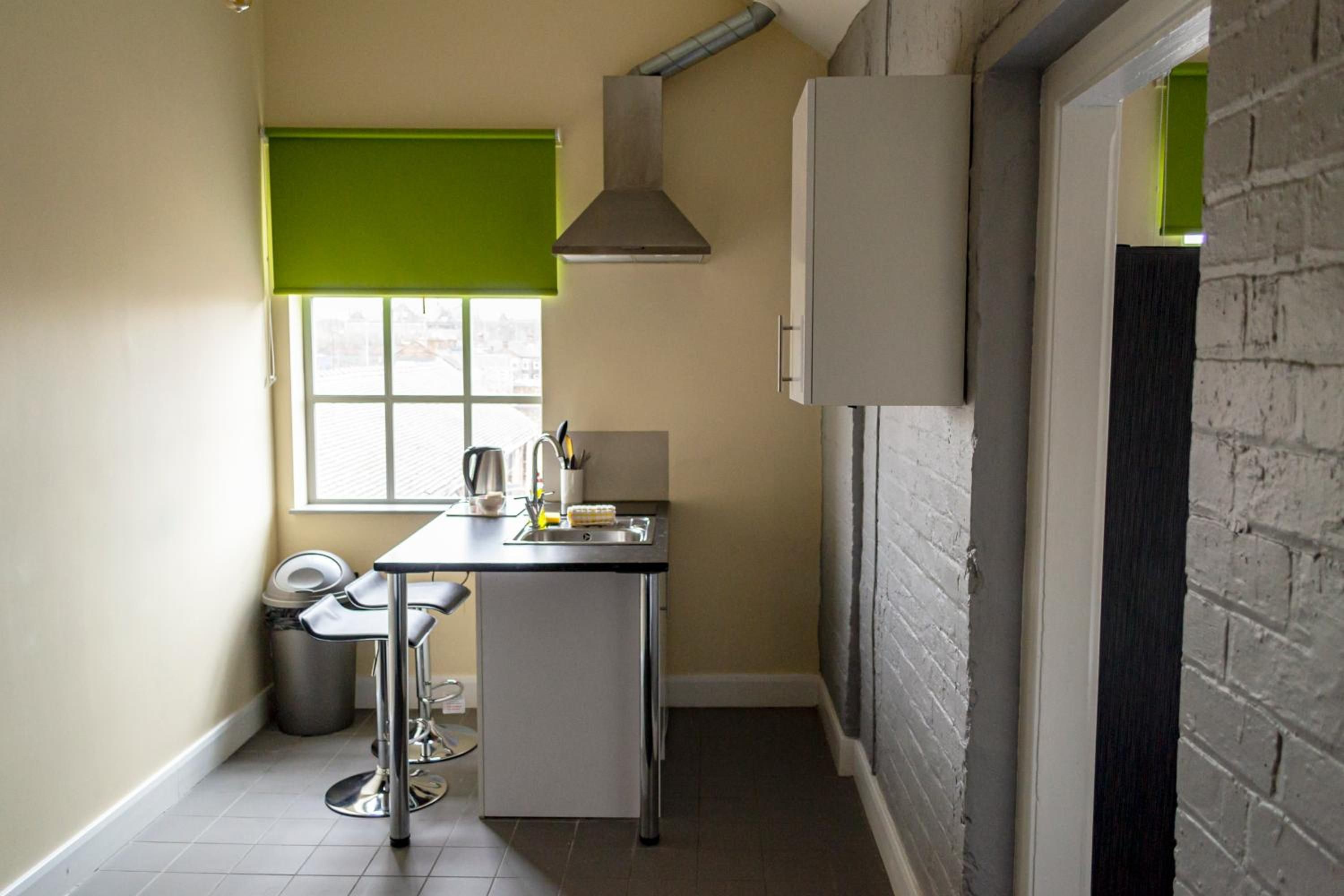A compact kitchen with a window, a sink, and a trash bin.