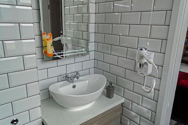 A bathroom with a white sink, a mirror, and a telephone.