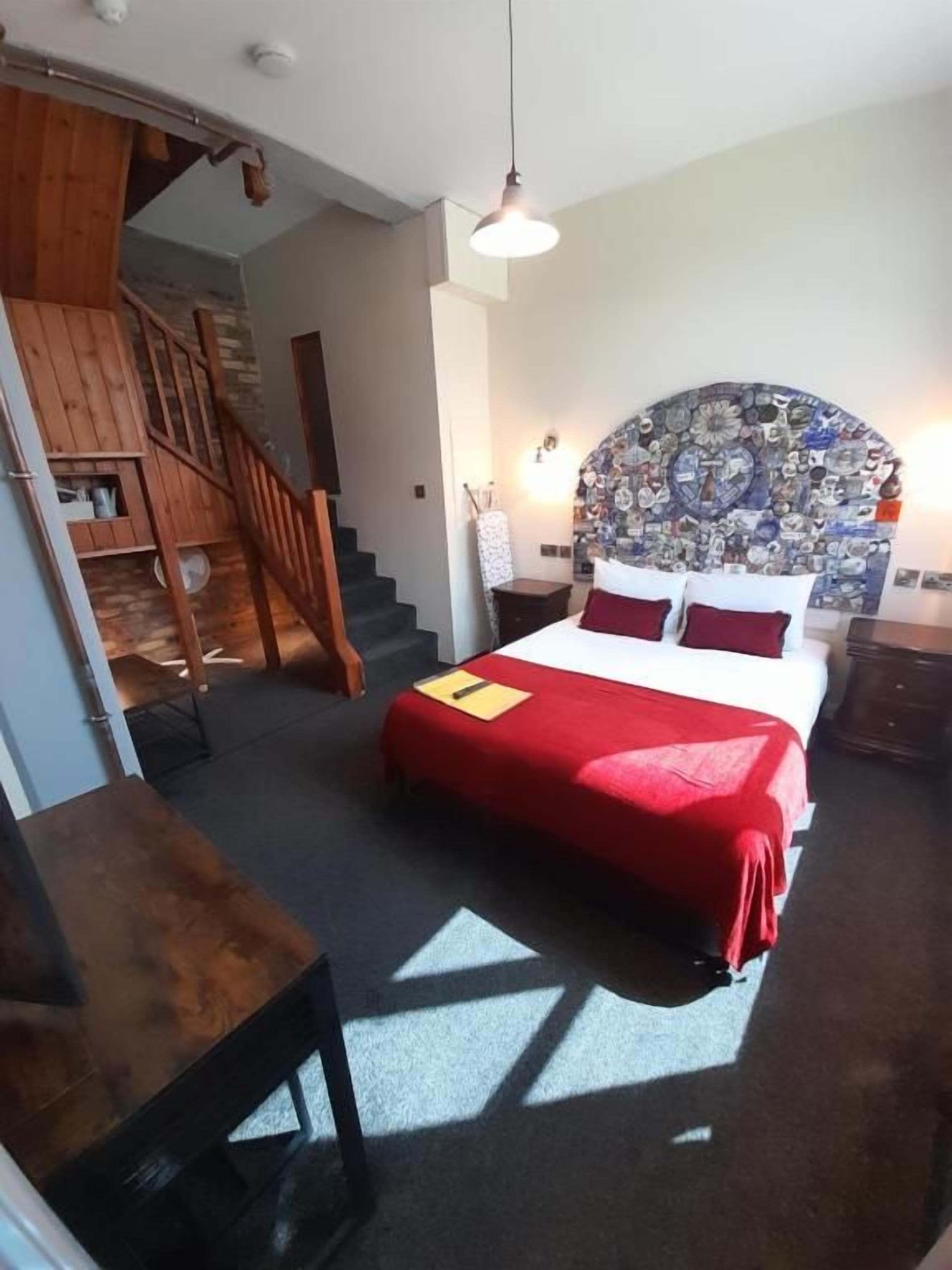 A bedroom with a bed, a wooden staircase, and a headboard with a mosaic design.