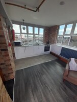 A kitchen with a large window, white cabinets, and a brick wall.