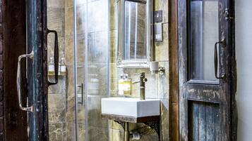 A bathroom with a marble wall, a white sink, a toilet, a potted plant, and a wooden door.