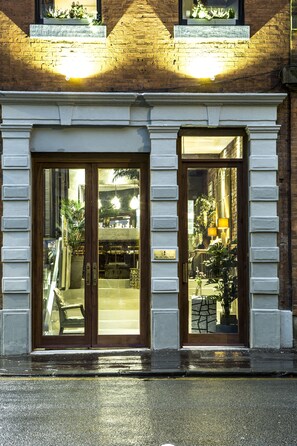A building with two large glass doors, a brick facade, and a sign indicating a hotel. - The Cow Hollow Hotel (Manchester)