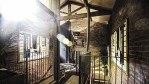 A narrow hallway with a wooden ceiling, brick walls, and a metal railing. - The Cow Hollow Hotel (Manchester)
