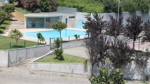 Un bâtiment moderne doté d’une piscine, entouré de verdure et d’une zone dallée.