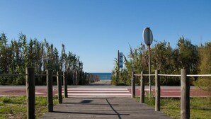 Une promenade en bois menant à une plage, avec un ciel dégagé.